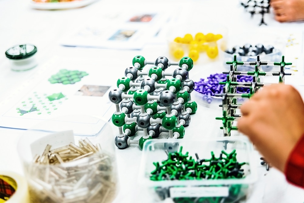 Group of students in biology class creating molecular models wit